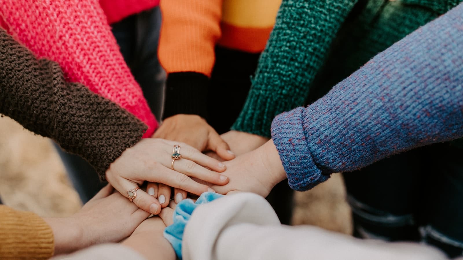 Close-up of a diverse group of people stacking their hands together in a show of unity and support